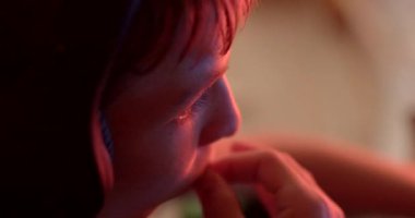 Kapüşonlu düşünceli bir çocuğu gösteren yakın plan bir resim. Ilık ışıkla hafifçe aydınlatılmış, sakin ve düşünceli görünüyor.