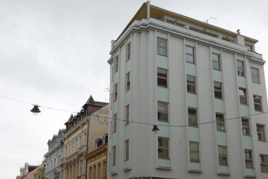 Gündüz vakti bulutlu bir gökyüzünün arka planına karşı çok sayıda penceresi olan büyük bir bina, benzersiz bir atmosfer yaratıyor.