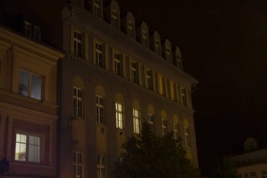 Geceleri pencereleri bol olan büyük bir bina güzelce aydınlatılıyor ve karanlık zemine çarpıcı bir manzara yaratıyor.