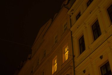 Pencerelerin bol olduğu büyük bir bina gece boyunca güzelce aydınlatılır ve canlı bir atmosfer yaratır.