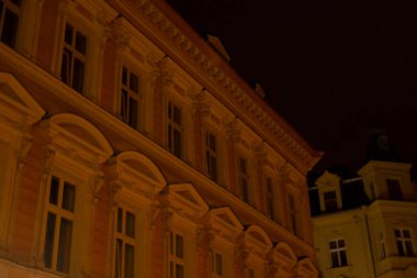 Sayısız parlak pencereyle süslenmiş büyük bir bina gece boyunca güzelce aydınlatılır ve karanlığa karşı çarpıcı bir görüntü yaratır.