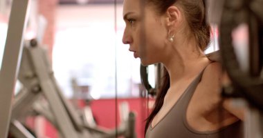 Bir atletle ağırlık hareketi, vücut eğitimi teknolojisi kararlı bir kadın modern bir spor salonunda kablo üzerinde çalışıyor, güç ve zindeliğe odaklanıyor..