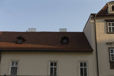 Değişik pencereleri ve farklı bacaları olan çarpıcı bir çatı çizgisi berrak mavi bir gökyüzüne karşı duruyor ve zamansız tarihi binaların sıra dışı mimarisini gözler önüne seriyor.