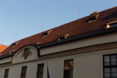 The captivating rooftop view showcases a historic building that features a beautifully designed decorative facade, various antennas, and numerous windows set against an open and clear sky