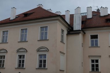 Bu çarpıcı dış görünüş, canlı kırmızı çatısı, geniş pencereleri ve dramatik bir gökyüzüne karşı eşsiz bir şekilde tasarlanmış beyaz bacaları olan iyi korunmuş tarihi bir binayı vurguluyor.