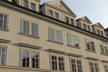 Birden fazla pencere bulunan tarihi bir binanın ön cephesi, kentsel bir ortamda, yapının karmaşık mimari tasarımını etkin bir şekilde vurgulayarak görülebilir.