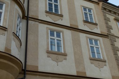 Tarihi bir binanın güzel cephesi, mimari mirasının özünü yansıtan çeşitli dekoratif unsurlarla birlikte karmaşık bir pencere düzenini sergiliyor.