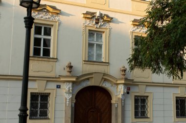 Bu resim, karmaşık dekoratif ayrıntıları ve güzel hazırlanmış ahşap kapıyla karakterize edilmiş son derece tarihi bir binanın ön görüntüsünü sergiliyor.