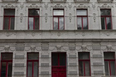 Çarpıcı kırmızı pencerelerle donatılmış büyük ve etkileyici bir bina ve tüm çekiciliğini ve karakterini arttıran kırmızı bir kapı.