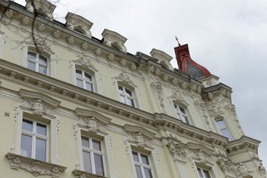 Zirvesinde çarpıcı bir kırmızı bayrak sallayan büyük beyaz bir bina var, dikkatleri üzerine çekiyor.