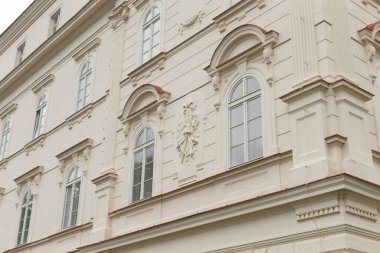 Çok sayıda penceresi olan büyük beyaz bir bina var ve özellikle zamanı tutmak için yanında bir saat gösteriyor.