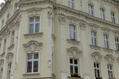 Çok sayıda pencereyle karakterize edilmiş büyük ve etkileyici beyaz bir bina sokağın köşesinde görkemli bir şekilde duruyor.