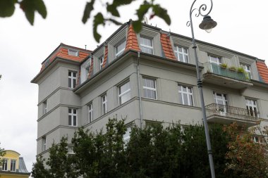 Çatısını süsleyen kırmızı karolardan oluşan büyük ve etkileyici bir bina dikkat çeken eşsiz bir mimari stil sergiliyor.