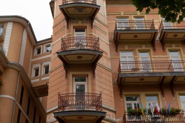 Yüksek ve şık tasarlanmış balkon bolluğu ve geniş doğal ışık için sayısız pencereyle donatılmış bir bina.