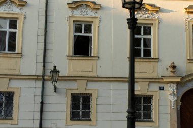 Büyüleyici bir binanın ön cephesinde açık bir pencere ve kentsel bir arka plana dayalı bir sokak lambası bulunur.