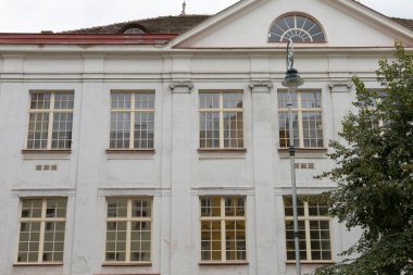 Tarihi bir binanın ön cephesinde geniş pencereler ve karmaşık mimari ayrıntılar yer almaktadır.