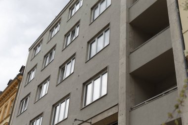 Güneşsiz bir günde, bulutlu bir gökyüzünün zeminine çarpan sayısız pencere ve balkonun bulunduğu büyük, etkileyici bir bina.