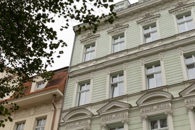 Önünde duran bir ağaç tarafından tamamlanmış önemli sayıda pencereye sahip önemli ve etkileyici bir bina.