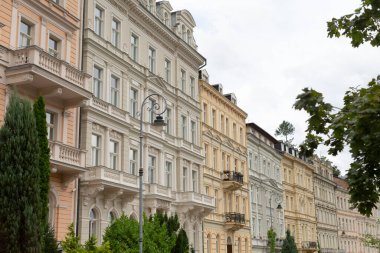 Muhtelif mimari tarzlar sergilenen, hareketli bir şehir caddesi boyunca uzun bir sıra bina düzgünce dizilmiştir.