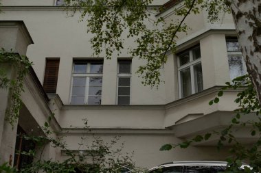 Çok katlı bir binanın ön cephesinde çok sayıda pencere ve yemyeşil alan