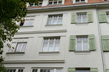 Her penceresinde büyüleyici yeşil panjurlarla süslenmiş büyük, güzel, beyaz bir bina. Hoş bir zıtlık ve çekici bir görünüm yaratıyor.