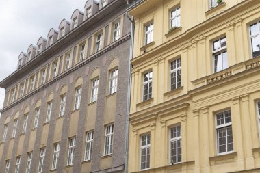 Daha küçük bir yapının yanında, çok sayıda penceresi olan ve ilginç bir mimari karşıtlık yaratan büyük bir bina var.