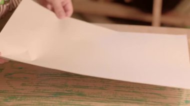 Kağıdı ellerle karton üzerine yapıştırarak, öğrenci kağıt ürünü elini zarifçe birbirine bağlar. Parça boş kağıdı canlı, renkli, dokulu bir yüzey boyunca hareket ettirir, yaratıcılığını gösterir.