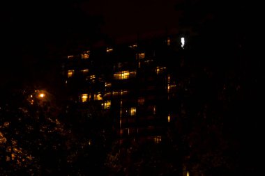 A somewhat blurry photograph depicting a building illuminated at night, showcasing its lights against the backdrop of darkness clipart