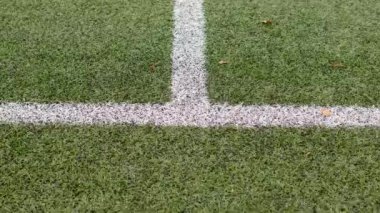 Beyaz çizgiler bir spor sahasının yapay çim arka planında belirgin şekilde kesişiyor