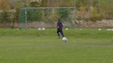 Bir çocuk CZ, Kralupy yakınlarındaki bir yetişkinle çimenlik alanda oturan futbol topuna doğru sevinçle koşuyor, 12.10.24