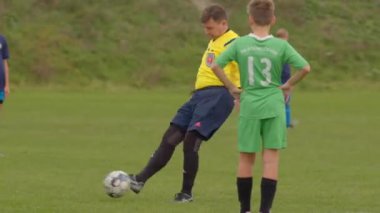 CZ, Kralupy, 12.10.24 'te sahada bir hakem ve hevesli bir oyuncunun yer aldığı canlı bir gençlik futbol sahnesi.