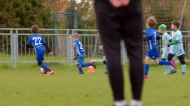 Genç oyuncular, CZ, Unhost, 10.10.24 gibi çeşitli arka plan aktivitelerinin ortasında sahada enerjik bir şekilde bir futbol maçına katılıyorlar.