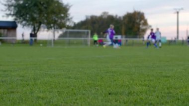 Bokeh etkisi, sahada futbol oynayan oyuncular coşkulu oyuncuların yemyeşil bir çim tarlasında yarıştığı heyecan verici bir gençlik futbolu oyunu yaşanıyor.