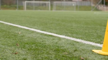 Spor sahasında durum, arka planda atletlerin hareketi. Sarı koni. Sarı bir güvenlik konisi stratejik olarak bir spor sahasının sınırına yerleştirildi.