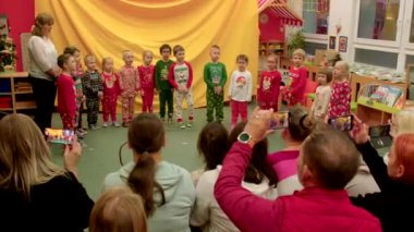 Çocuklar bir anaokulunda ebeveynleri için gösteri yapıyorlar. Erken çocukluk sanat eğitimi. Aile olarak gurur ve neşe. Aileler akıllı telefonlardan anıları yakalıyor. 12.12.2024 Vinohrady, Prag