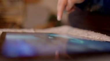 Bir birey, dokulu bir yüzey arkaplanı üzerinde dinlenirken bir tablet aygıtı ile etkileşim halindedir