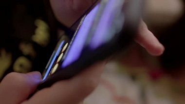 Akıllı telefonu tutan bir elin yakın çekimi ekrandaki ilgi çekici yansımasını gözler önüne seriyor.