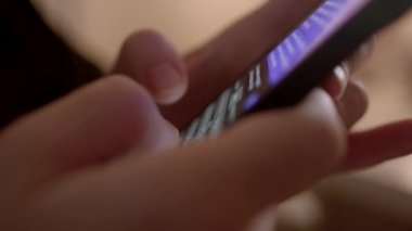 Bir el akıllı telefonu sıkıca kavrar, ekranda gösterilen mesajlaşma uygulamasına dikkatle konsantre olur.