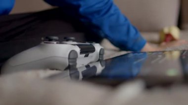 Mutlu bir çocuk, yumuşak halı zemininde otururken video oyunu oynamaktan derinden zevk alır.