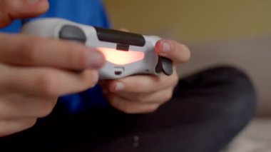 Video oyunu oyununa daldırılırken bir PlayStation denetleyicisini yakalayan iki elin yakın plan görüntüsü
