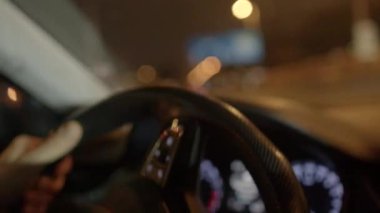 Gece saatlerinde araba kullanırken bir direksiyon simidinin iç görünümü gözlenebilir