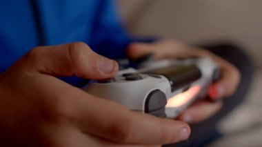 Canlı bir mavi arkaplana karşı bir video oyunu denetleyicisini ustalıkla kullanarak ellerin yakın plan görüntüsü