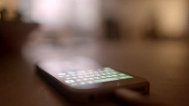 Bir akıllı telefon ahşap bir yüzeye yerleştirilmiş bir klavye gösteriyor ve arka plan yumuşak odaklı.