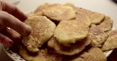 Güzel desenli bir tabağa yerleştirilmiş taze ev yapımı patates kekleri servis eden bir el.