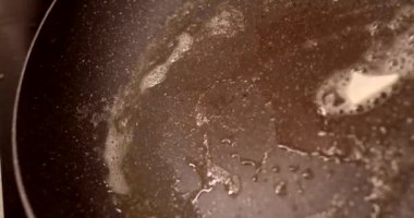 Mutfak arka planının altını çizen fırına konmuş yağ dolu bir tava.