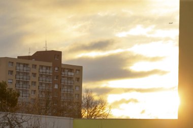Parlak güneş bir pencereden güzel bir şekilde parlıyor, sıcak ışık huzmeleri saçıyor, arka planda yüksek bir bina görünüyor.