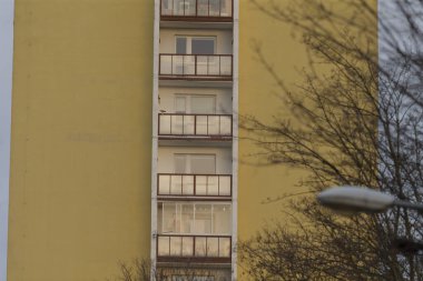 Balkonları olan parlak sarı bir bina ve tam önüne yerleştirilmiş bir sokak lambası büyüleyici atmosferi güçlendiriyor.