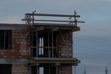 Şu anda sağlam bir tuğla bina inşa ediliyor ve ustalıkla üstüne inşa edilen iskeleler işçilerin erişimlerini artırıyor.