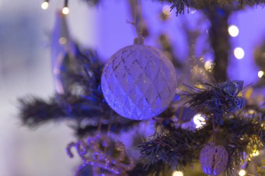 Bu, çok güzel dekore edilmiş bir Noel ağacının yakın bir görüntüsü. Çok sayıda dekorasyonun yanında göz kamaştırıcı mor ışıklar da var.