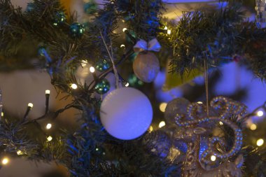 Çok güzel süslenmiş bir Noel ağacının detaylı bir yakın çekimi. Etrafında çeşitli şenlikli dekorasyonlar ve parıldayan ışıklar sergileniyor.